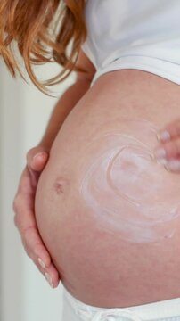 Pregnant woman rubbing cream on her belly