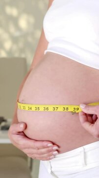 Pregnant woman measuring her bump