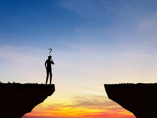 Thinking about the risk, businessman stands deciding on the cliff gap