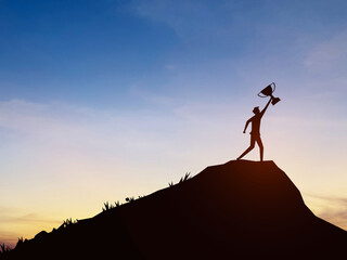 Businessman holding a trophy on top of a mountain. Concept of successful business or determination