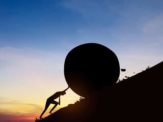 Silhouette of businessman pushing a big rock up a hill. Concept of determination and effort to solve problems. Hard work