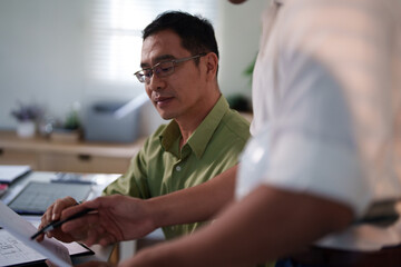 A team of engineers evaluating project risks and discussing construction timelines at their...