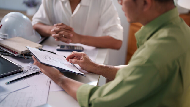 Engineers collaborating on project details with blueprints, material samples, and technical diagrams on the table.