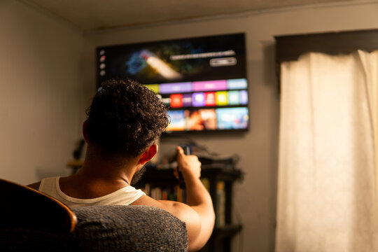 Man choosing streaming platform on smart tv at home