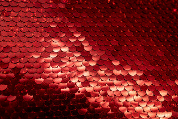Defocused macro abstract texture background of a textile surface of glittering stitched red sequins