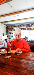 An elderly woman is enthusiastically reading a book in a cafe.