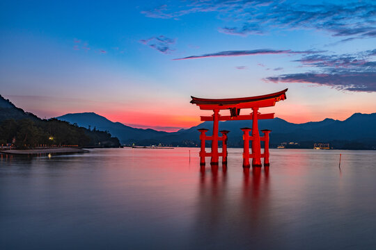 Hiroshima, Japan - July 27, 2023: Itsukushima Shrine's grand torii gate lit up at magic hour time