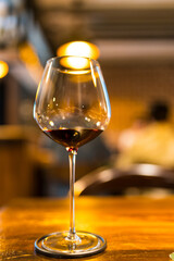 A red wine glass is elegantly placed table setting with lights creating a enhances the warm and festive ambiance.