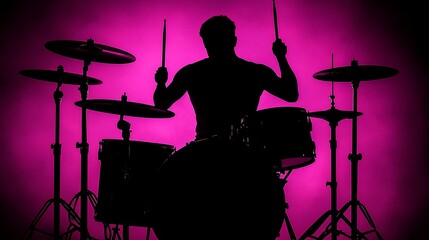 Fototapeta premium Silhouette of a drummer playing drums against a pink background.