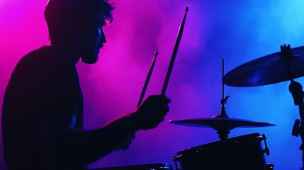 Fototapeta premium Drummer silhouetted in vibrant stage lighting, playing drums.