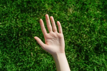 A human hand is raised against a vibrant green background
