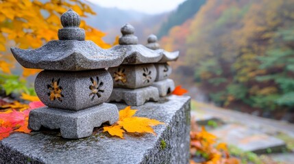 Stone lanterns adorned with autumn leaves sit on a moss covered stone wall, a tranquil autumn scene in a misty mountain setting. The soft light and