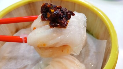 close up image of picking up hakau or steamed shrimp dumplings with chopsticks