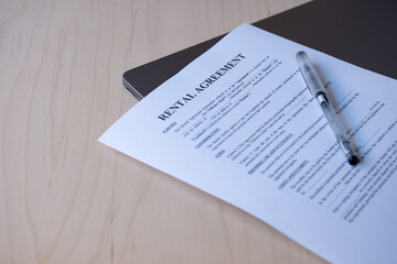Rental Agreement Contract on Space Grey Laptop with Pen on Wooden Background