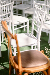 Brown chair among white chairs that were arranged at weddings that were arranged in gardens and lawns with sunlight and shadow