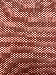 Fabric is woven from yarn in 3 colors are beige, orange and brown. close up