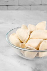 bowl of frozen dumplings on light background. Frozen semi finished dough products