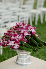 Orchid bouquet wrapped with banana leaves and placed on a silver tray, used in the traditional Thai morning wedding ceremony held in a garden