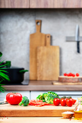 Healthy eating, cooking, food blogging background. Оak cutting board with broccoli, tomatoes, lettuce on cozy kitchen with wooden table, kitchenware and ingredients