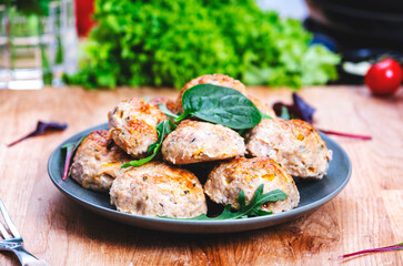 Baked chicken and turkey cutlets or meatballs with yellow paprika on kitchen table.