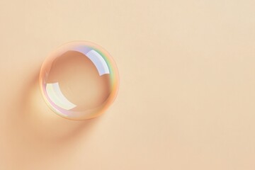A translucent soap bubble reflects rainbow hues on beige background