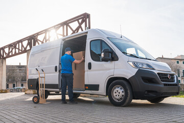 Fototapeta premium Delivery Worker Organizing Packages in Delivery Van. Delivery worker in a blue uniform arranging cardboard boxes inside an open van. Concept of logistics, distribution, and freight transportation.