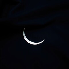 Obraz premium A delicate crescent moon shape casts an ethereal glow on a dark fabric, crescent, lunar