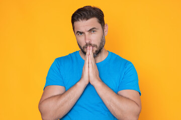 Christian Religion. Man praying. Isolated portrait of male pray. Closeup portrait of man praying hands, hoping isolated on yellow background. Human pray.