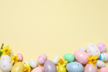 Happy Easter. Colorful eggs and yellow flowers on a pastel color background, space for text or advertising