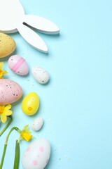 Happy Easter. Colorful eggs, bunny ears and yellow flowers on a pastel color background, space for text or advertising