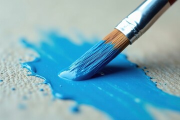 Close-up view of a paintbrush applying vibrant azure paint to a textured surface, showcasing the fluidity and texture of the paint