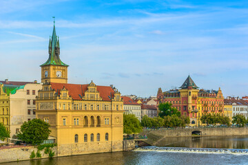 A beautiful waterfront view of the Bedřich Smetana Museum in Prague, Czech Republic, showcasing its historic architecture along the Vltava River with famous city landmarks in the background