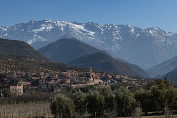 Fototapeta premium Grand Atlat mountains and Orica valley view with traditional houses and mosque minaret snowy mountains on background Morocco