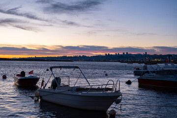 Fototapeta premium Boats silhouetted sunrise sky background. Peaceful sunrise scene with fishing boats anchored in the harbor on calm sea. Golden horizon, early morning at bay