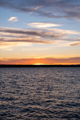 Naklejka premium Beautiful golden sunrise over a calm sea with distant horizon. Peaceful sunrise scene with the sun reflecting on calm water. Early morning at bay