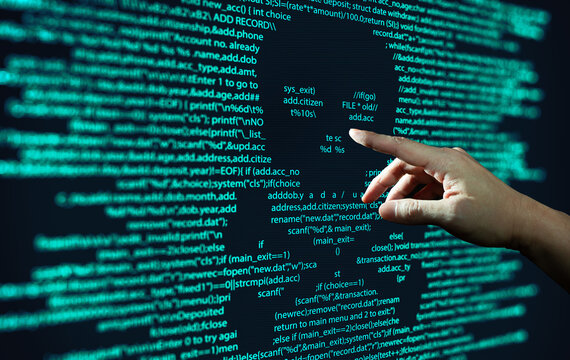 Human hand points at abstract Modern tech of Programming code screen with skull. Computer Virus, Malware, and Hacker Attack Concept.