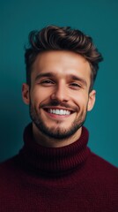 Obraz premium Confident young man smiling in a turtleneck sweater against a teal wall background during the day