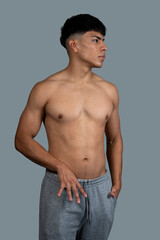 Fototapeta premium Young latino male model posing shirtless in studio, showing his physique