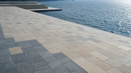 Obraz premium A serene waterfront area with patterned paving stones beside calm water.