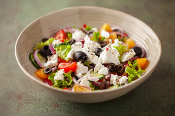 Greek salad of fresh cucumber, tomato, sweet pepper, arugula, red onion, feta cheese and olives with olive oil. Healthy food.