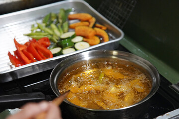 野菜の素揚げをする女性