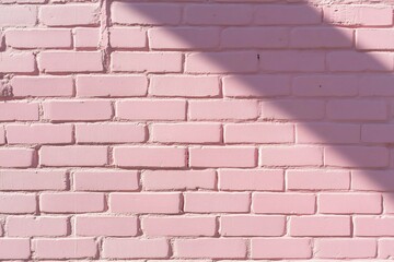 Obraz premium Pink brick wall with shadows background pattern, for use as wallpaper or texture