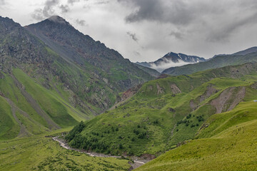 river between mountain under grey sky