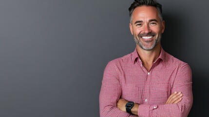 Confident middle-aged man smiling with arms crossed in a neutral-toned setting