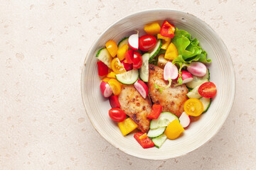 Chicken fillet grill with vegetable salad in a bowl on the table. Top view