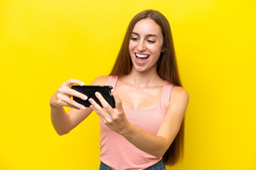 Young caucasian woman isolated on yellow background playing with the mobile phone