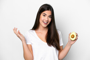 Young Brazilian woman holding an avocado isolated on white background with shocked facial expression