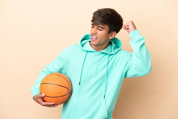 Handsome young basketball player man isolated on ocher background celebrating a victory