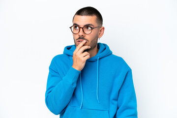 Young caucasian man isolated on white background With glasses and having doubts