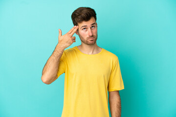 Young caucasian handsome man isolated on blue background with problems making suicide gesture